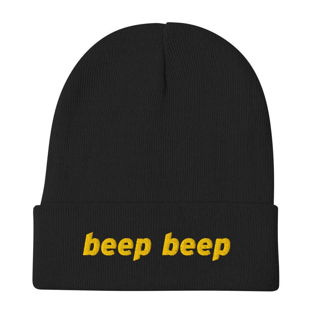 A black knit beanie with “beep beep” embroidered on the front in yellow thread.