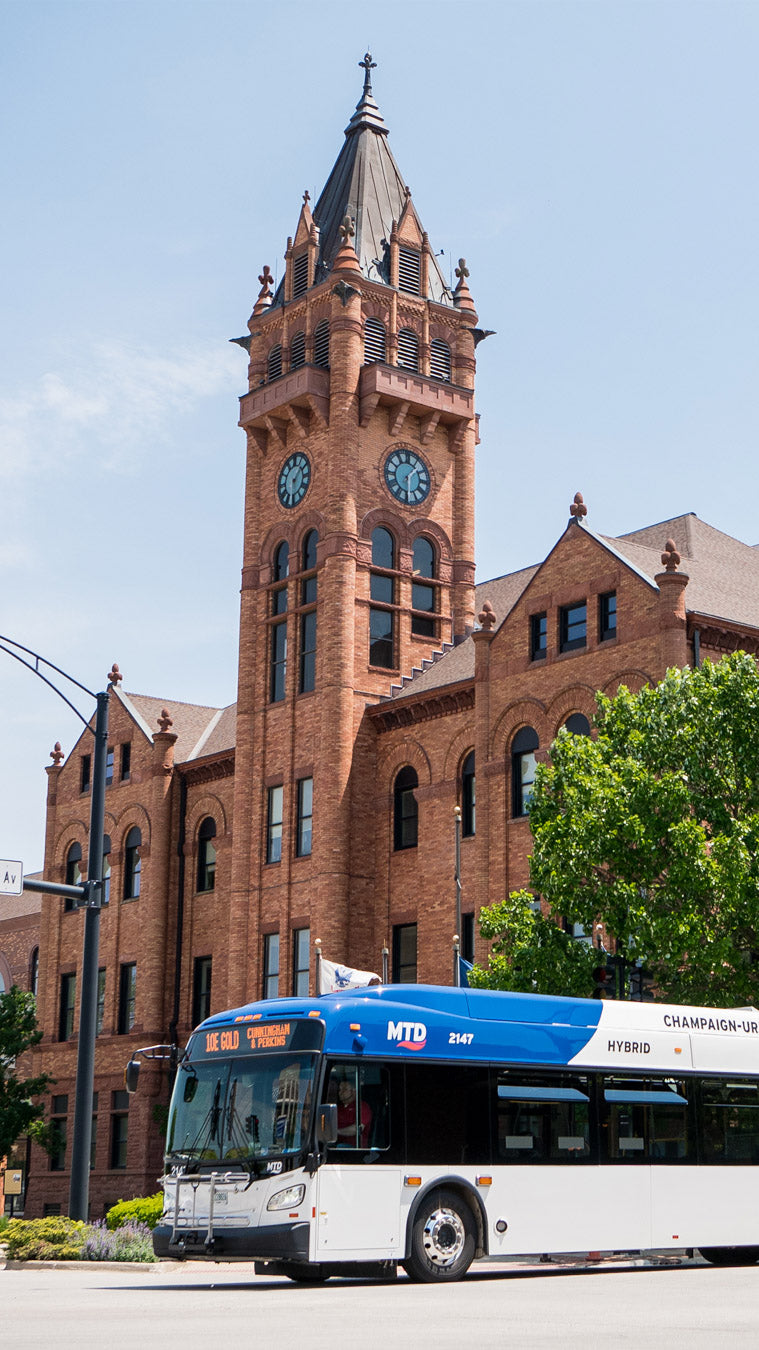 An MTD bus driving past a historic red brick building with a clock tower.
