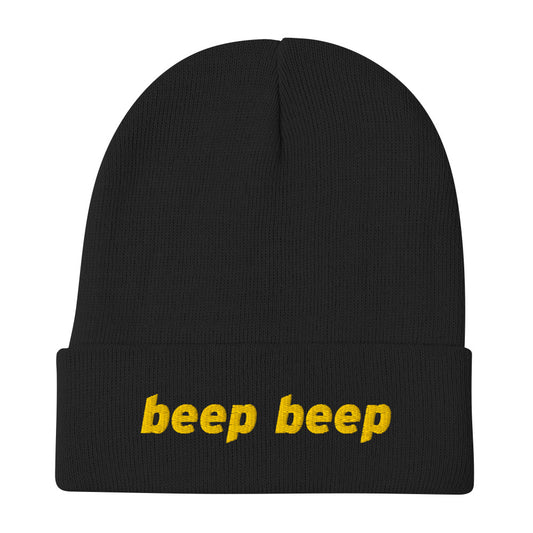 A black knit beanie with “beep beep” embroidered on the front in yellow thread.